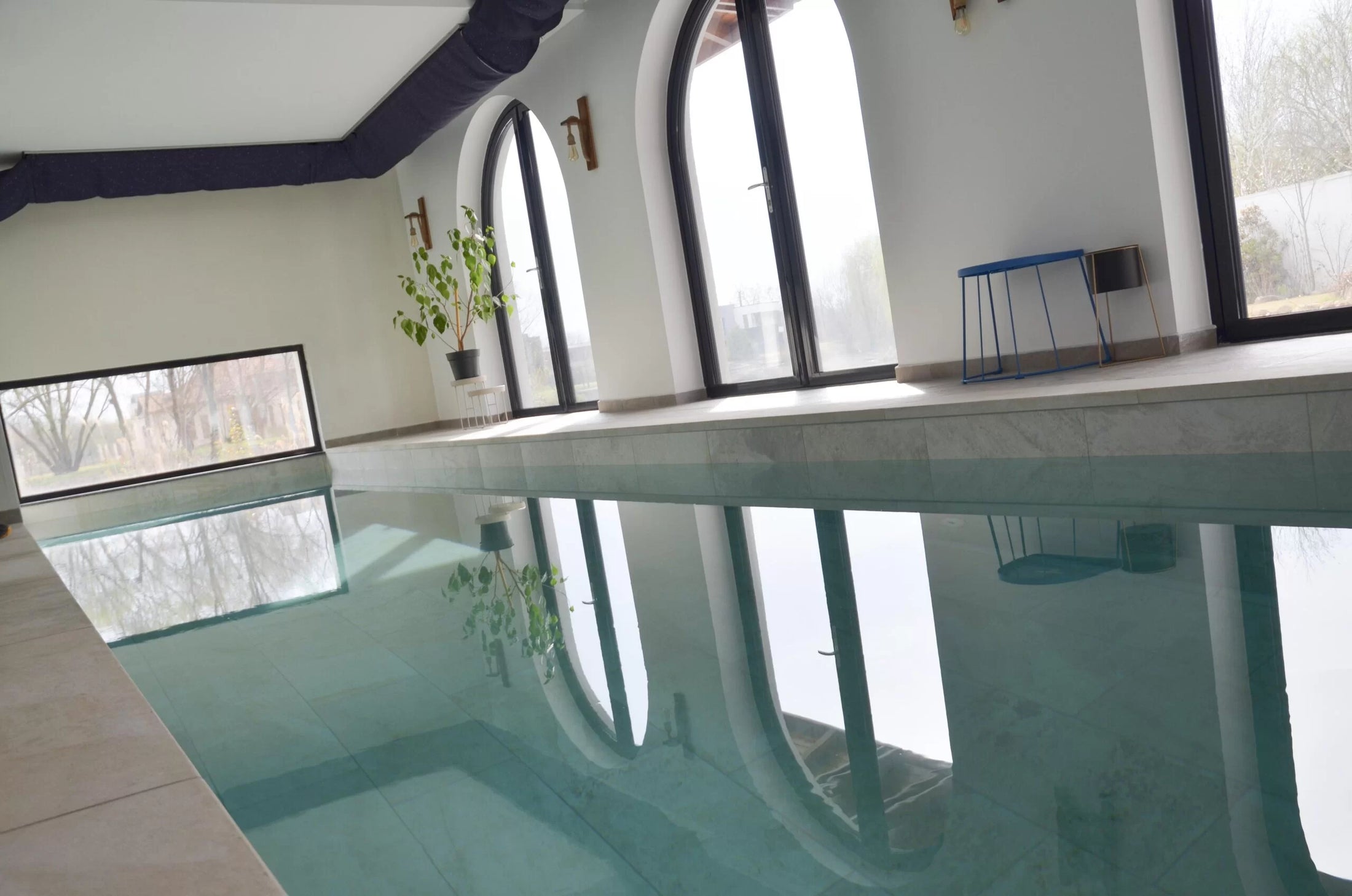 Piscină interioară realizată de AS Piscine, cu ferestre arcuite și apă turcoaz