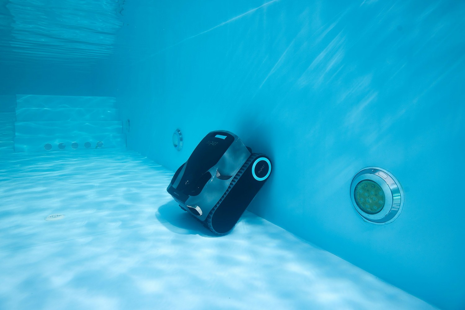 Robot de piscină urcând pe peretele bazinului, lângă duza de aspirație